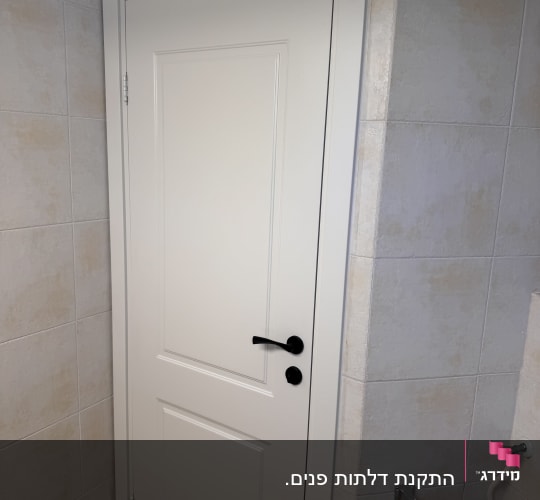 דלת לבנה עם ידית שחורה בחדר אמבטיה